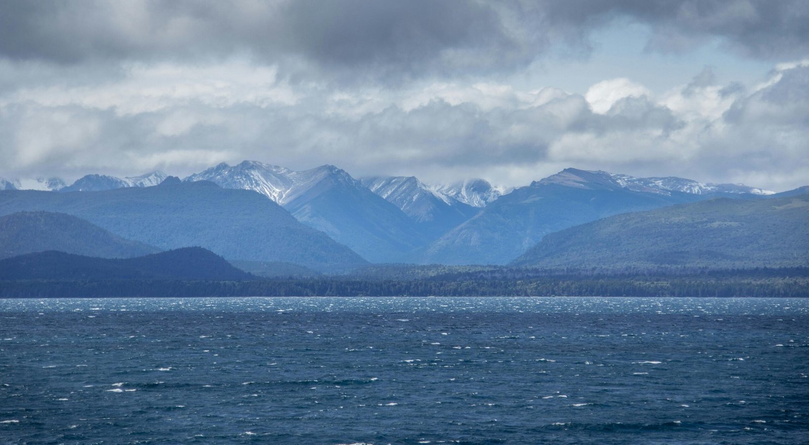 Serene view of the Andes mountains with snow caps over Nahuel Huapi Lake in Bariloche, Argentina.